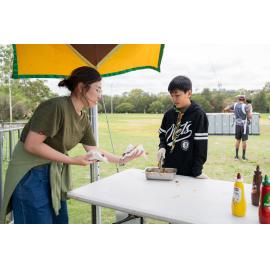 Scout volunteer serving food at a sausage sizzle stall at the 2026 Australia Day celebrations