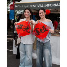 Girls holding red calligraphy banners at a Lunar New Year festival, 2026