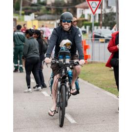 A man riding a bike accompanied by a dog at the Cork & Fork festival, Putney